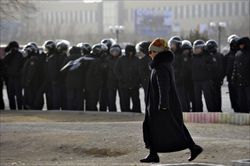 Una donna cammina davanti a un cordone di polizia durante le proteste nella città kazaka di Aktau.