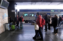 Viaggiatori guardano i cartelloni elettronici con i ritardi dei treni alla stazione Termini di Roma.