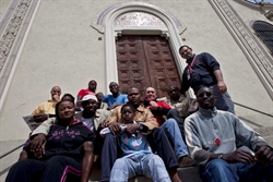 Alcuni dei 31 profughi africani davanti alla chiesa della borgata Ferria, a Forno di Coazze, in alta Val Sangone (foto: Paolo Siccardi/Sync).
