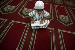 Medio Oriente. La speranza di pace negli occhi delle nuove generazioni. Un bimbo palestinese prega leggendo il Corano (foto Ansa).