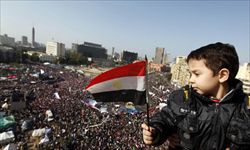 Un bambino con la bandiera egiziana mentre osserva piazza Tahrir gremita di manifestanti (Ansa). 