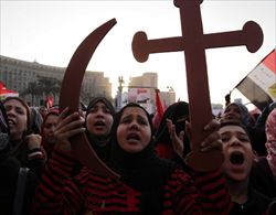 Donne egiziane in piazza con la croce cristiana e la mezzaluna musulmana (Ansa).