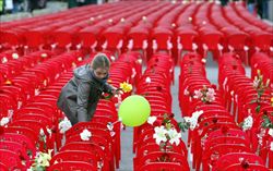 Una bambina depone fiori su ognuna delle 11.541 sedie vuote nella principale strada di Sarajevo, per onorare le vittime dell'assedio alla città avvenuto vent'anni fa (Ansa).