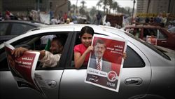 Militanti dei Fratelli Musulmani festeggiano l'elezione di Morsy (nel poster) in piazza Tahrir, al Cairo (foto del servizaio: Reuters).