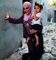 Una donna con la figlia in una via di Aleppo colpita dai bombardamenti (foto Reuters).
