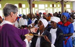 Un missionario comboniano portoghese distribuisce la Comunione durante la Messa della prima domenica di Quaresima in un sobborgo povero di Lusaka, la capitale dello Zambia. Foto Nino Leto. 