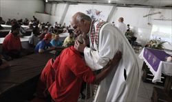 Un sacerdote abbraccia un barbone in un centro di accoglienza per i senzatetto a San Paolo in Brasile (Reuters).