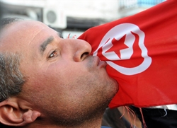Un dimostrante bacia la bandiera tunisina durante gli scontri nella capitale contro l'aumento dei prezzi e la disoccupazione.