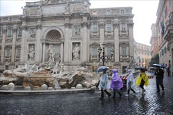 Un gruppo di turisti sotto la pioggia a fontana di Trevi a Roma.