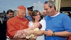 Il presidente dei vescovi italiani, cardinale Angelo Bagnasco, con una famiglia.
