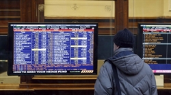 Un uomo guarda le quotazioni di Borsa su un monitor di un'agenzia di banca, a Milano, il 26 gennaio 2011 (foto Ap/Luca Bruno).