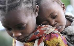 Una bimba africana si carica il fratellino sulla schiena (foto: Reuters). 