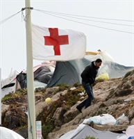 Migranti tunisini nel porto di Lampedusa vicini a una postazione della Croce Rossa.