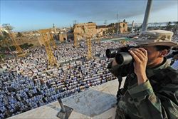 Un ribelle controlla dall'alto i fedeli radunati in Piazza dei Martiri, nella capitale libica.