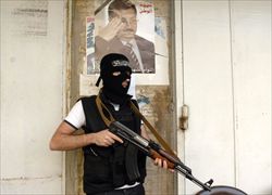 Un libanese sunnita armato davanti a un poster di Wissam al-Hasan (Reuters).