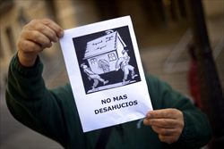 Uno spagnolo mostra un cartello dove si legge "Basta sfratti" (Reuters).