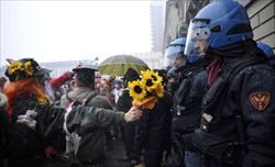Una manifestante No Tav offre un mazzo di fiori ai poliziotti schierati in tenuta antisommossa davanti alla sede della Regione Piemonte, in piazza Castello, sabato 28 gennaio. Foto di Giorgio Perottino/Reuters.