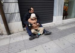 Un padre e un figlio chiedono la carità nella capitale greca (foto Ansa).