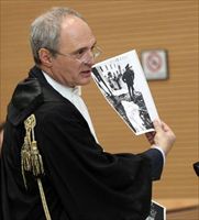 L'avvocato Piergiorgio Vittorini mostra le fotografie della strage alla giuria. Foto Ansa.