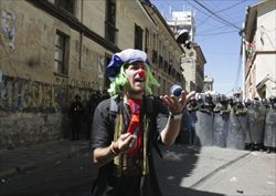 Un clown gioca con i gas lacrimogeni davanti ai poliziotti durante lo sciopero a La Paz (Reuters).