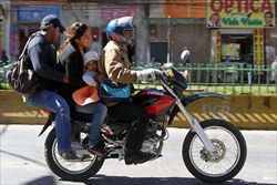Una famiglia boliviana in moto durante lo sciopero dei trasporti (Ansa).