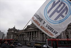 Un argentino sventola la bandiera della YPF davanti alla sede del Congresso a Buenos Aires (Reuters).