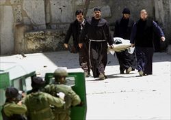 Padre Ibrahim Faltas e altri religiosi portano fuori dalla Basilica un palestinese ferito durante l'assedio del 2002 (Reuters).