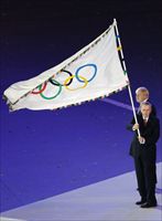 Jacques Rogge, presidente della Commissione olimpica con la bandiera dei giochi.