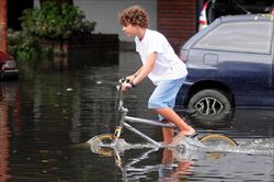 Un bambino argentino in bicicletta in mezzo all'acqua alta (Ansa).