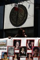 Una ragazza messicana mostra un manifesto con le foto di donne e bambine scomparse (Reuters).